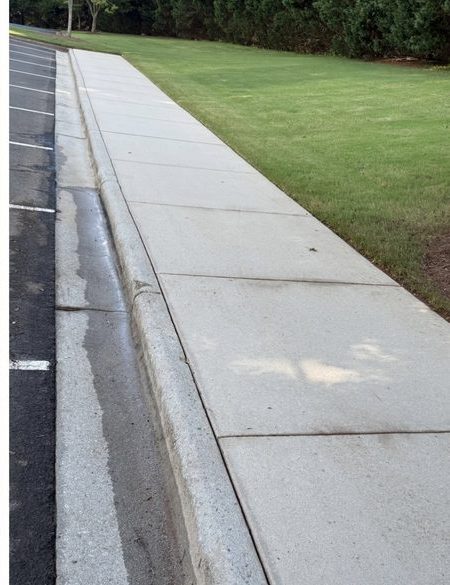 Clean commercial parking lot curb after professional pressure washing Raleigh NC