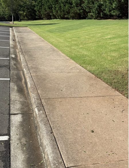 Stained commercial parking lot before pressure washing
